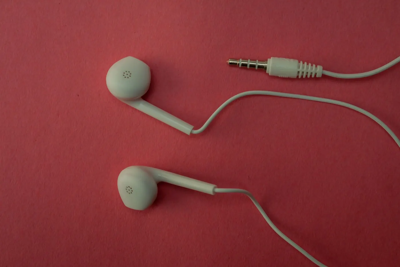 White earphones on a red surface