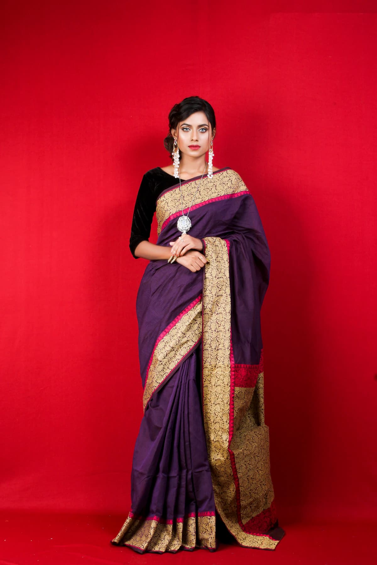 Woman in a purple and gold saree against a red wall